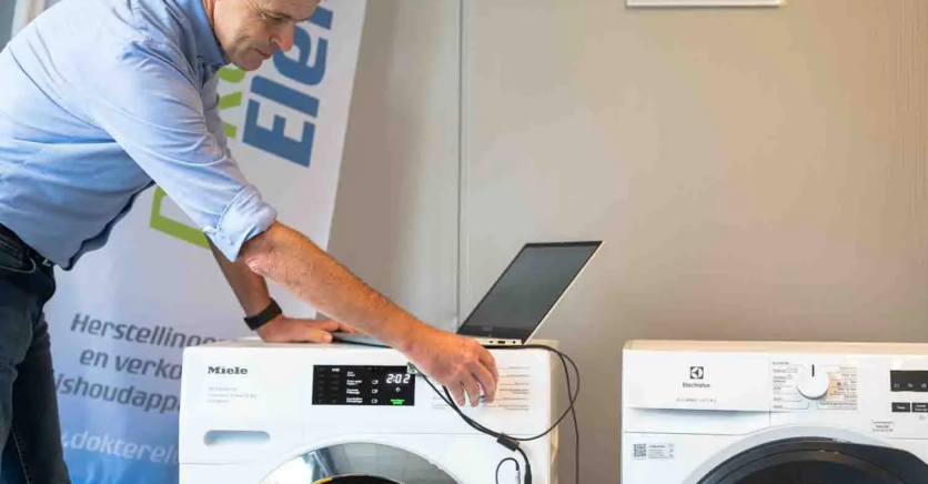 Marc Leyre van Dokter Elektro voert een vakkundige herstelling uit aan een wasmachine met een sensor en computer